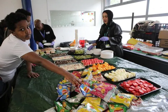 A young person at a buffet of fruit and snacks.