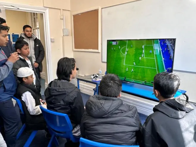 Young people playing a PlayStation football game