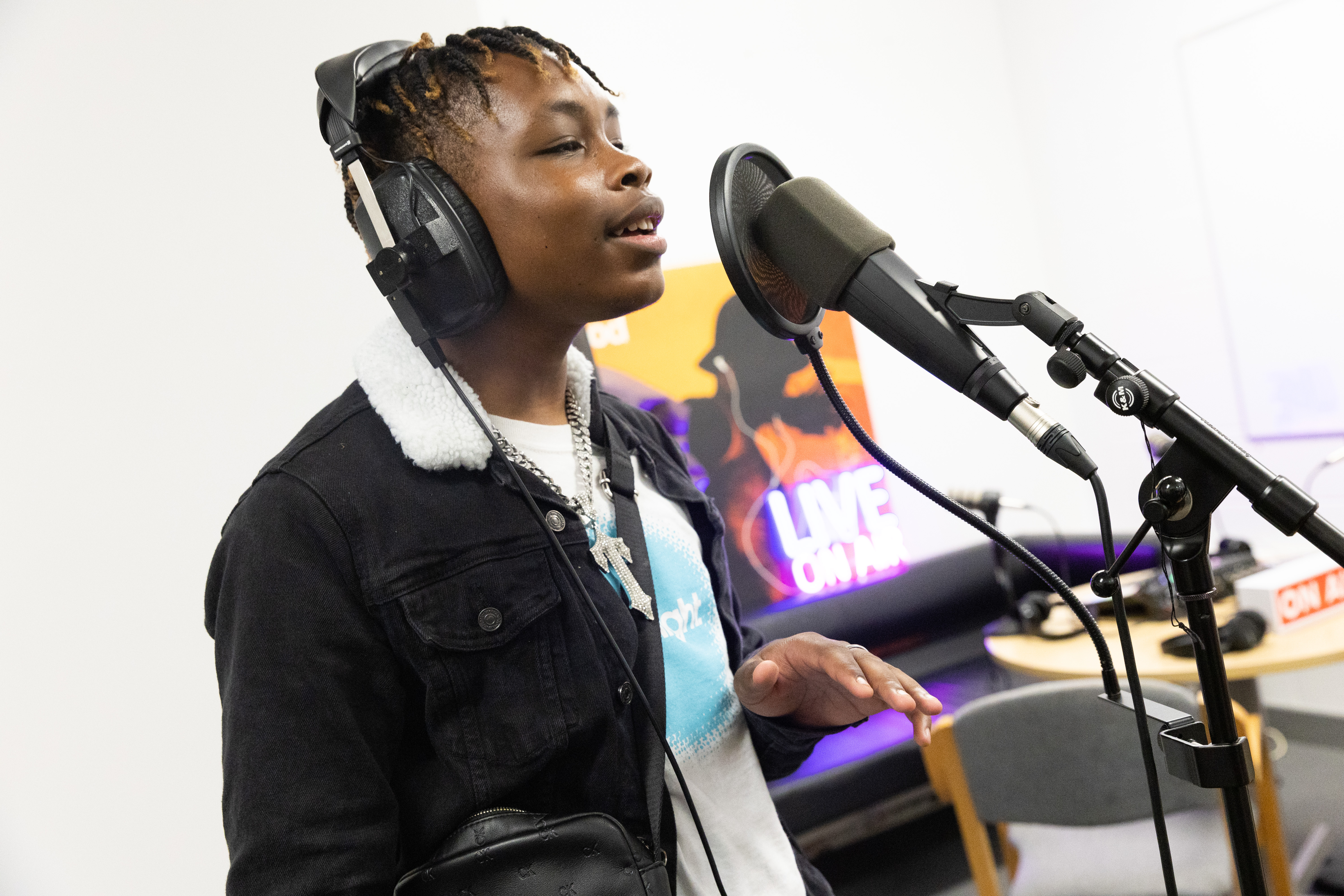 Youngster wearing headphones singing into a microphone on a stand with a pop guard